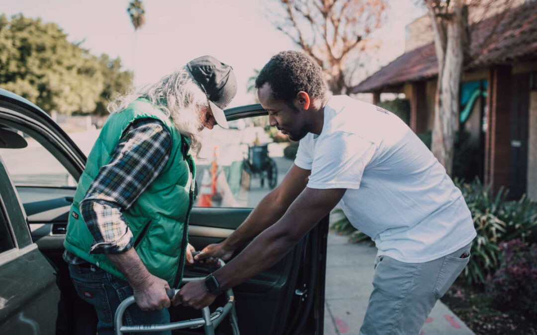 young man helping an elderly gentleman out of his vehicle